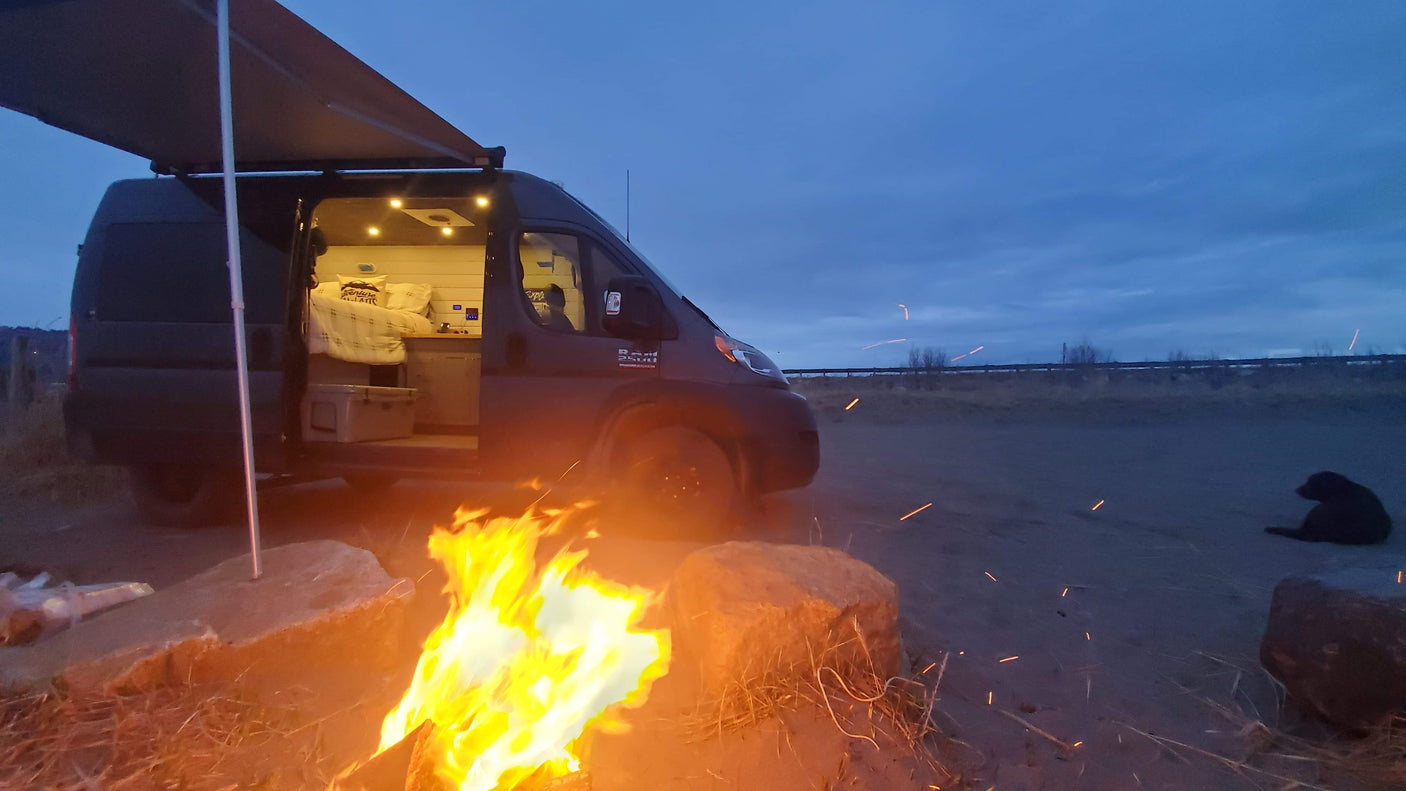 Cozy night camping! This RV rental offers a warm campfire, van life comfort, and a furry friend under a vast sky.