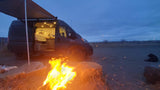 Cozy night camping! This RV rental offers a warm campfire, van life comfort, and a furry friend under a vast sky.