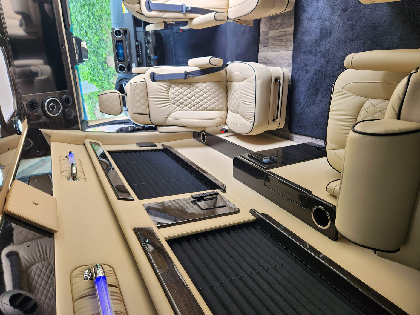 Plush cream leather seats and dark wood trim define this luxurious RV rental interior, featuring a central console and controls.