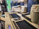 Plush cream leather seats and dark wood trim define this luxurious RV rental interior, featuring a central console and controls.