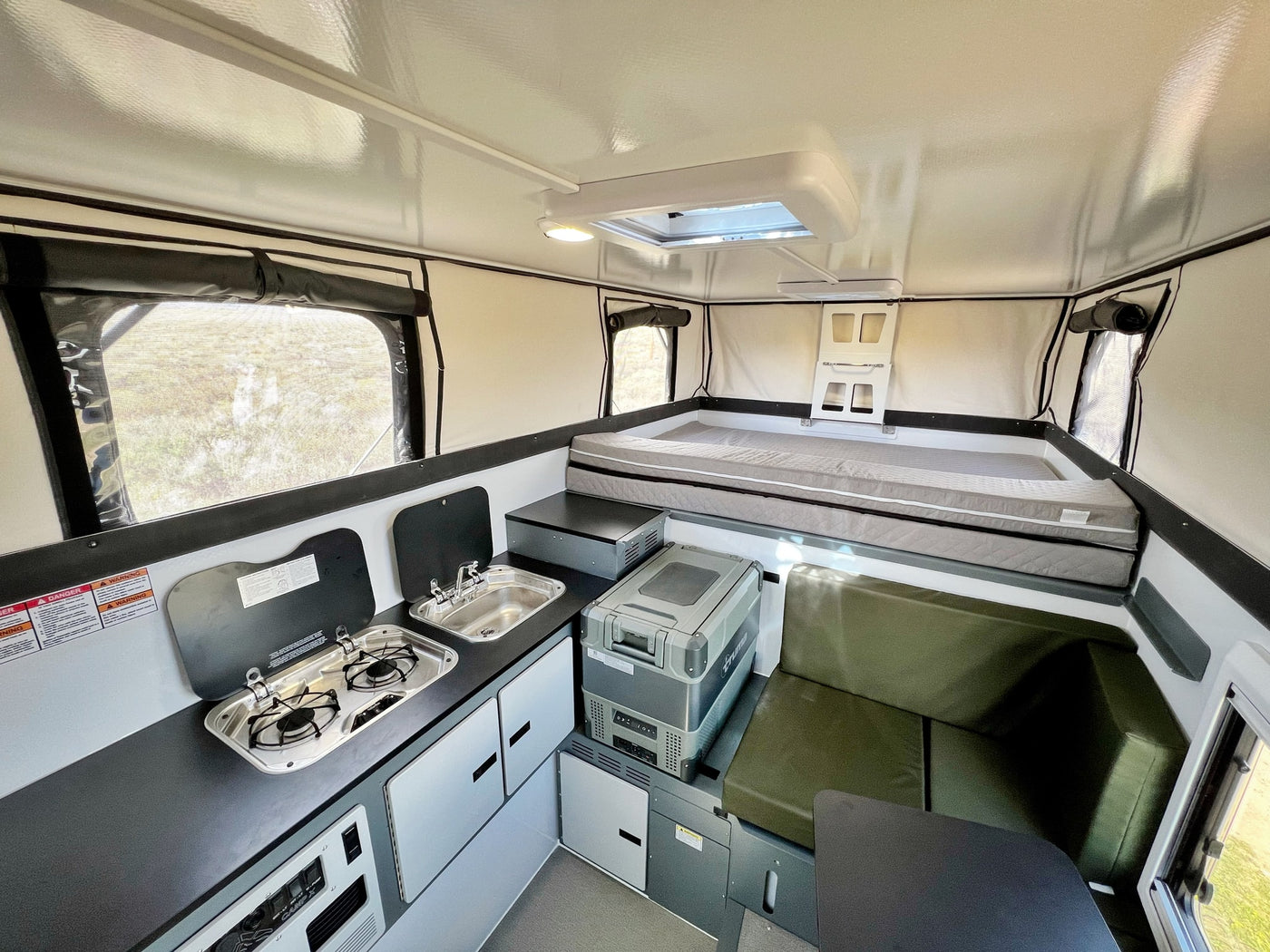 Modern rv rental interior showing a compact kitchen, comfortable bed, and versatile seating area in a pop-up camper. — photo 8