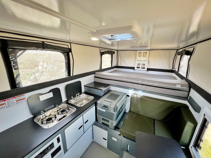 Modern rv rental interior showing a compact kitchen, comfortable bed, and versatile seating area in a pop-up camper. — photo 8