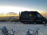 Enjoying golden hour with our Airstream RV rental camper van, outdoor chairs, and a dog at a scenic desert campsite.
