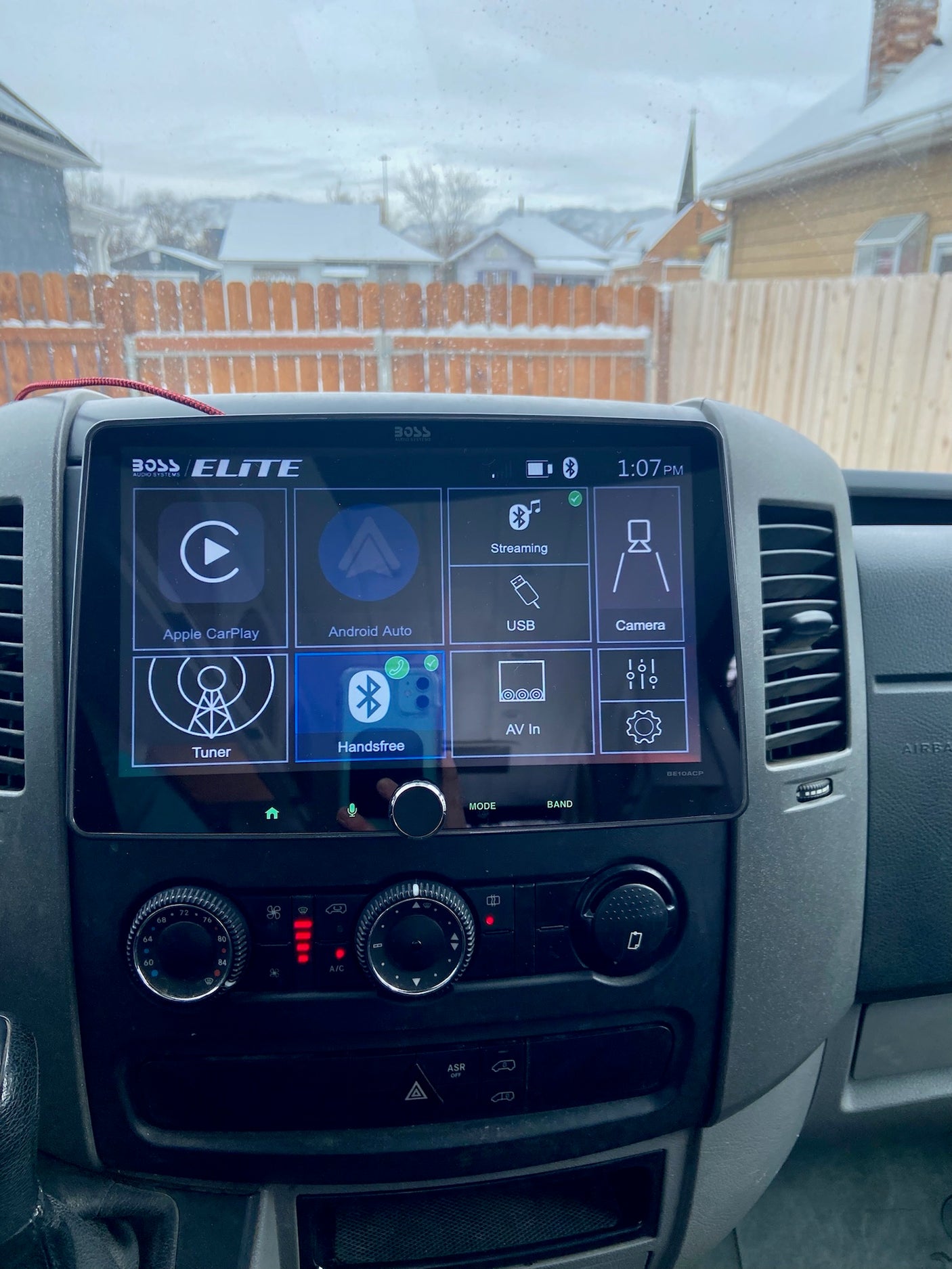RV rental: Dashboard with Boss Elite Apple CarPlay screen & climate controls. Snowy neighborhood visible outside.