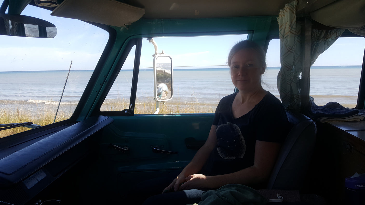 Woman inside an RV rental with ocean views. Cozy camper van experience by the sea.