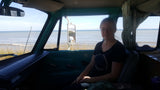 Woman inside an RV rental with ocean views. Cozy camper van experience by the sea.