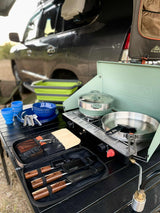 RV rental adventure: complete portable kitchen setup with stove, dishes, and knives for outdoor cooking.