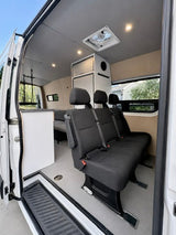 RV rental: Bright camper van interior with an open sliding door, a three-person bench seat, ceiling fan, and storage.