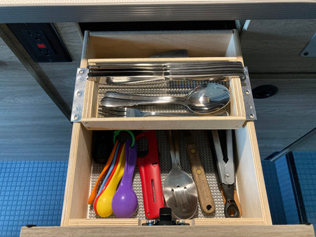 RV rental kitchen drawer: Organized silverware, colorful measuring spoons, & cooking utensils. Ready for your trip!