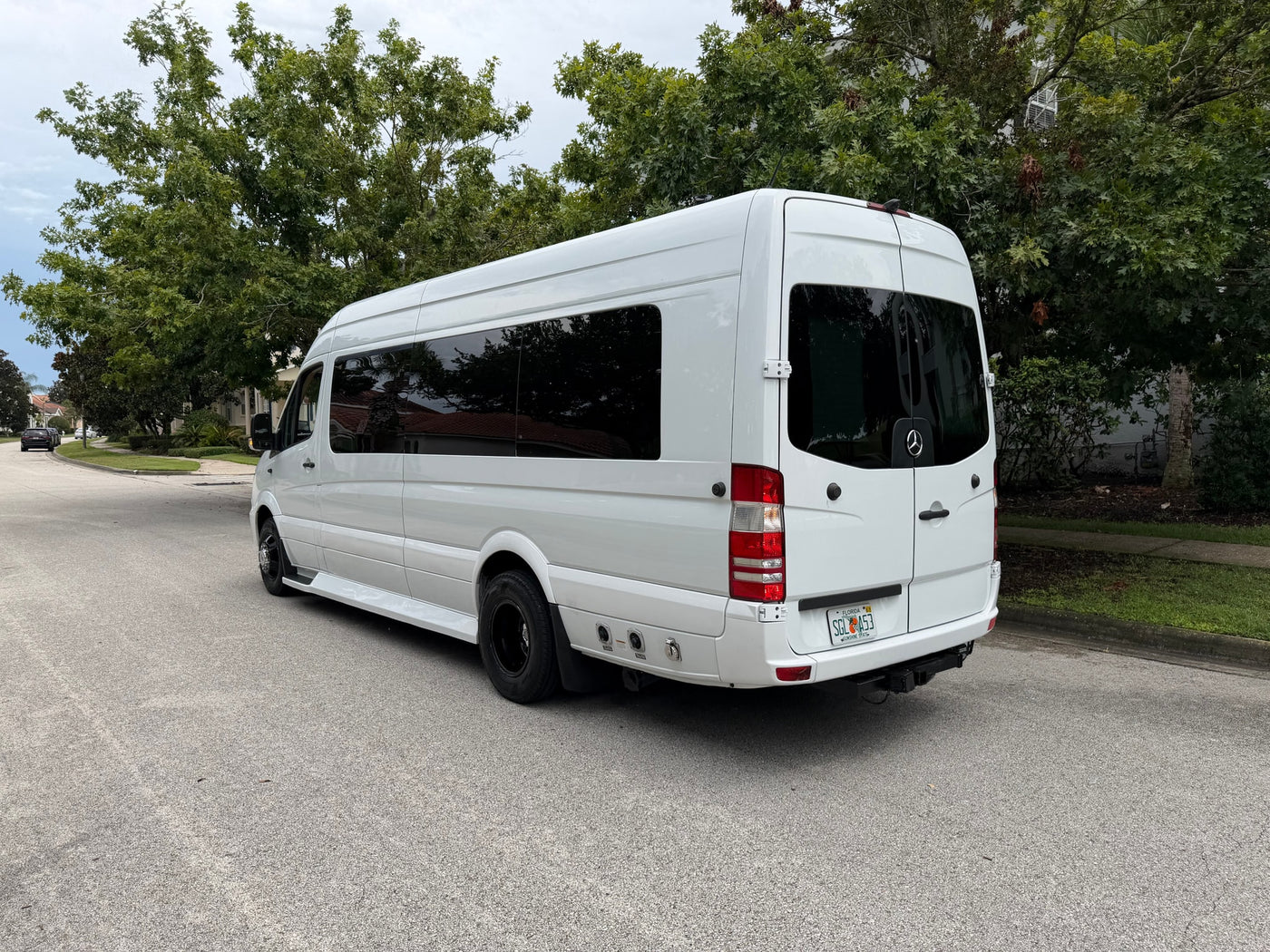 A white Mercedes-Benz Sprinter van, ideal for rv rental, with tinted windows parked on a residential street. — photo 3