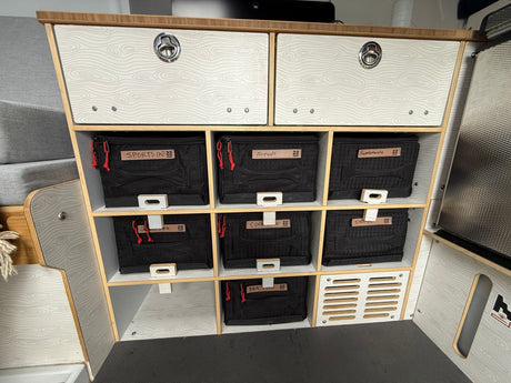 Organized rv rental storage: custom shelves, two drawers, and labeled bins for sports, bread, supplements, and dry food.
