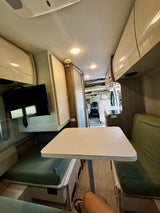 RV rental dinette, TV, and kitchenette in a bright, modern camper van interior.