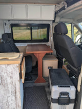 Experience freedom in this RV rental! Functional camper van interior with kitchen, table, overhead storage, & large fridge.