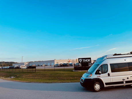 Silver Thor Motor Coach RV rental van parked at their factory/dealership, surrounded by other motorhomes under a clear sky.