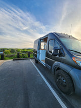 This sleek dark gray camper van rv rental features an open kitchen setup, perfect for your next road trip adventure.