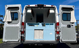 Open white camper van for RV rental, showing its custom light blue interior and patterned door panels.