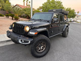 Black Jeep Gladiator with rooftop tent, ideal for an RV rental adventure. Ready for off-road camping trips.