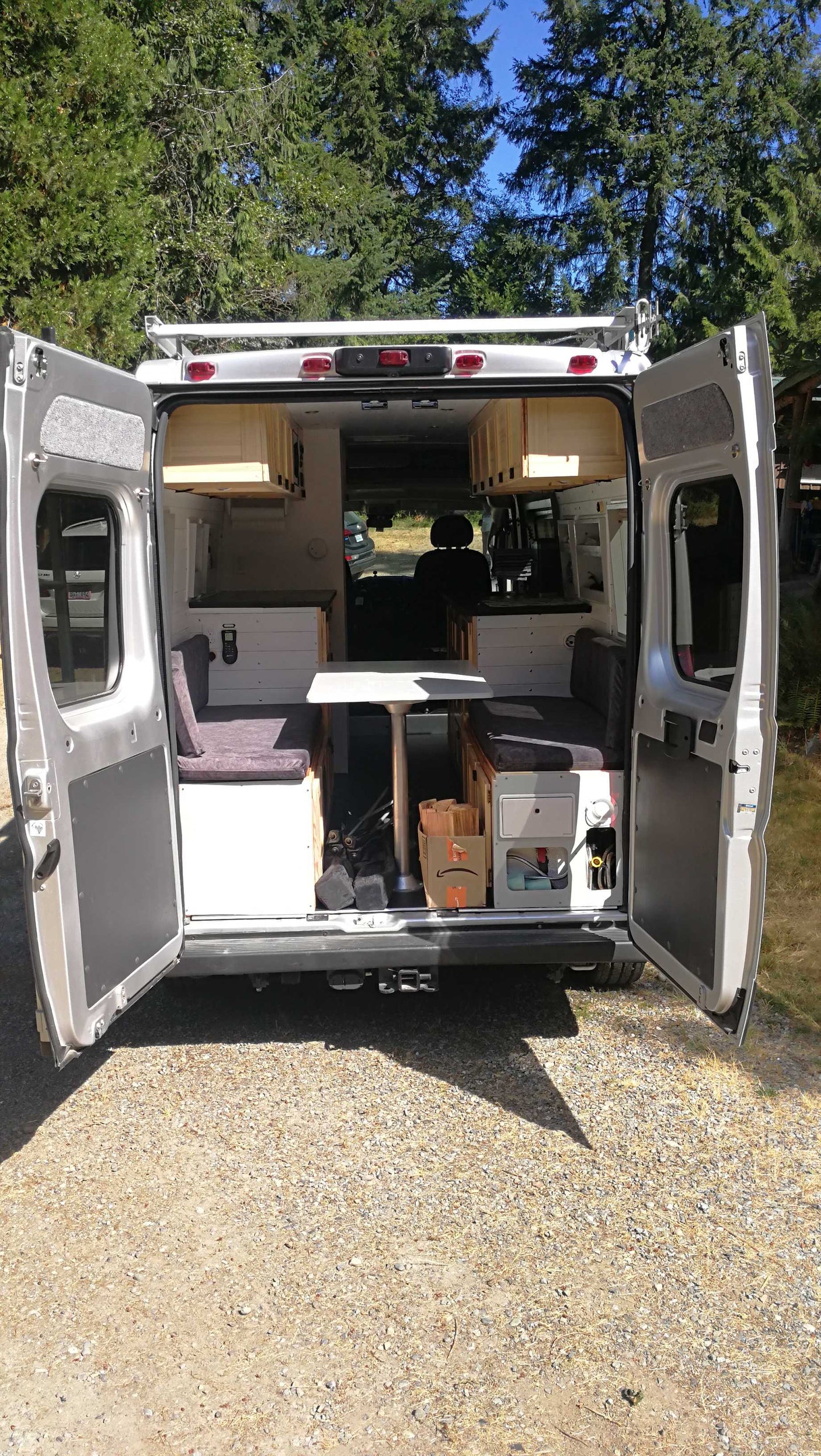 Rear view of an open silver customized camper van, showing its full interior setup. Ideal rv rental.