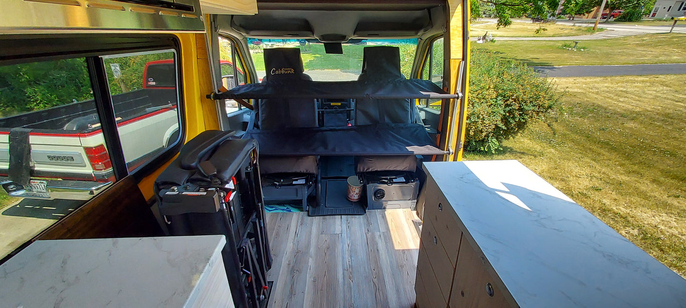 Explore this RV rental: a yellow camper van with front-seat bunk beds, a portable stove, and marble-look counters.