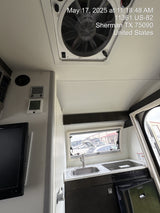 Explore this RV rental's compact interior, featuring a kitchen with sink and stove, refrigerator, overhead fan, and exterior view.