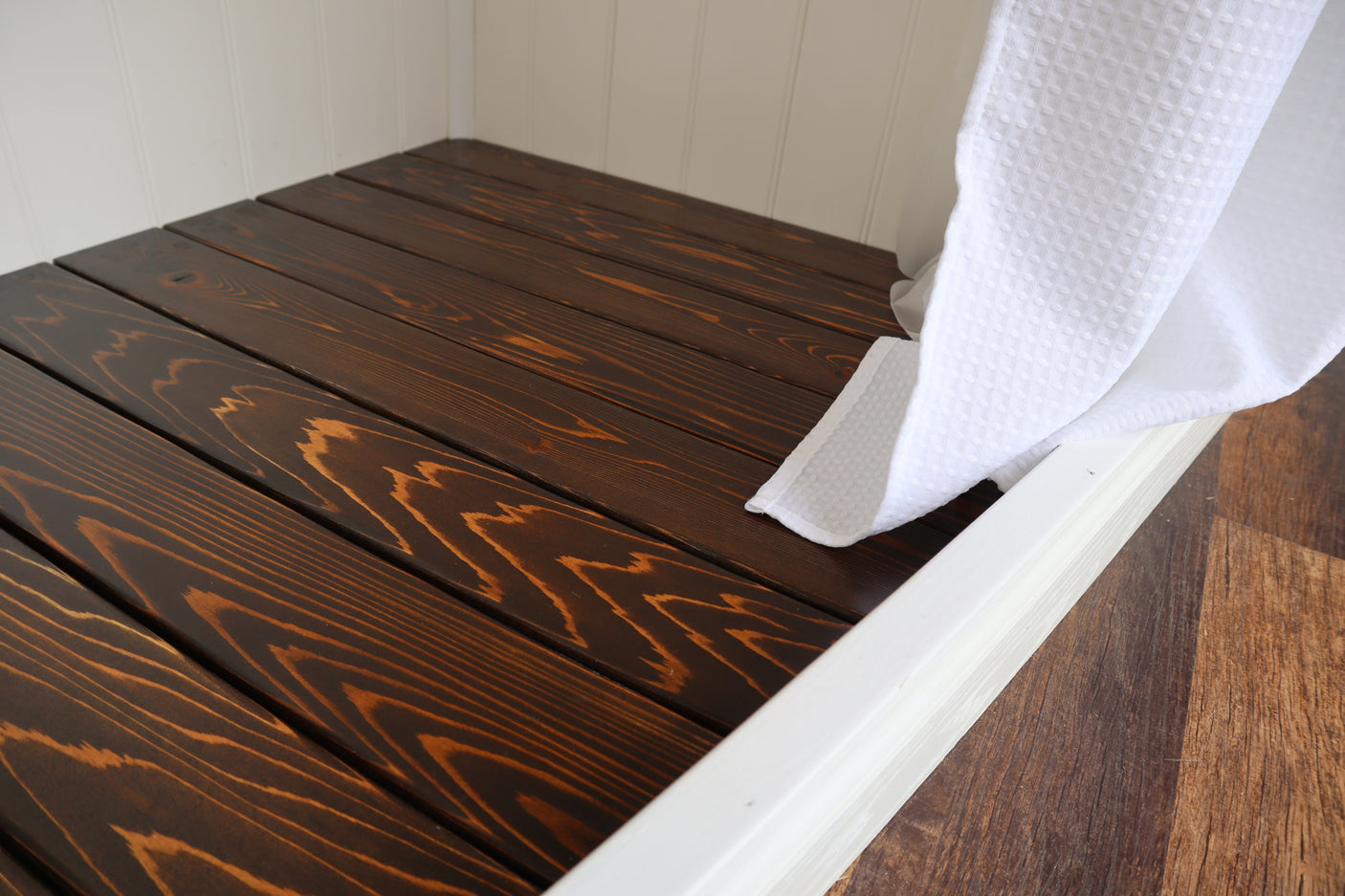 Cozy wood-slatted bench or bed in RV rental, with fresh waffle towel & white paneling. Compact comfort awaits.