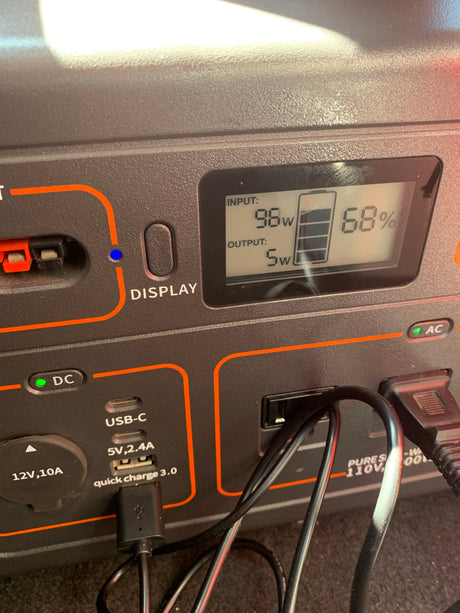A portable power station in an RV rental, showing 68% battery, 98W input, 5W output, ideal for camping power needs.
