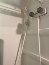 RV rental: Interior white shower with handheld showerhead, hose, and two clear knob water controls.