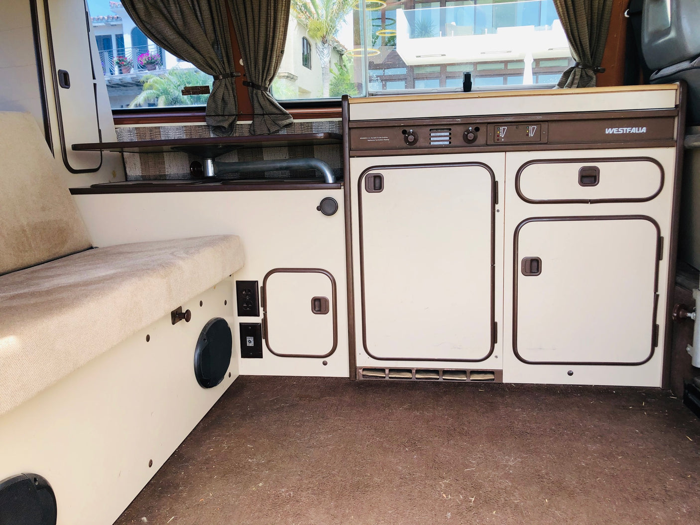 Westfalia RV rental interior: beige/brown, with comfortable bench & compact kitchenette for travel.