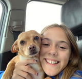 Young girl smiles, hugging a light brown dog in an RV rental. Ready for a pet-friendly journey!
