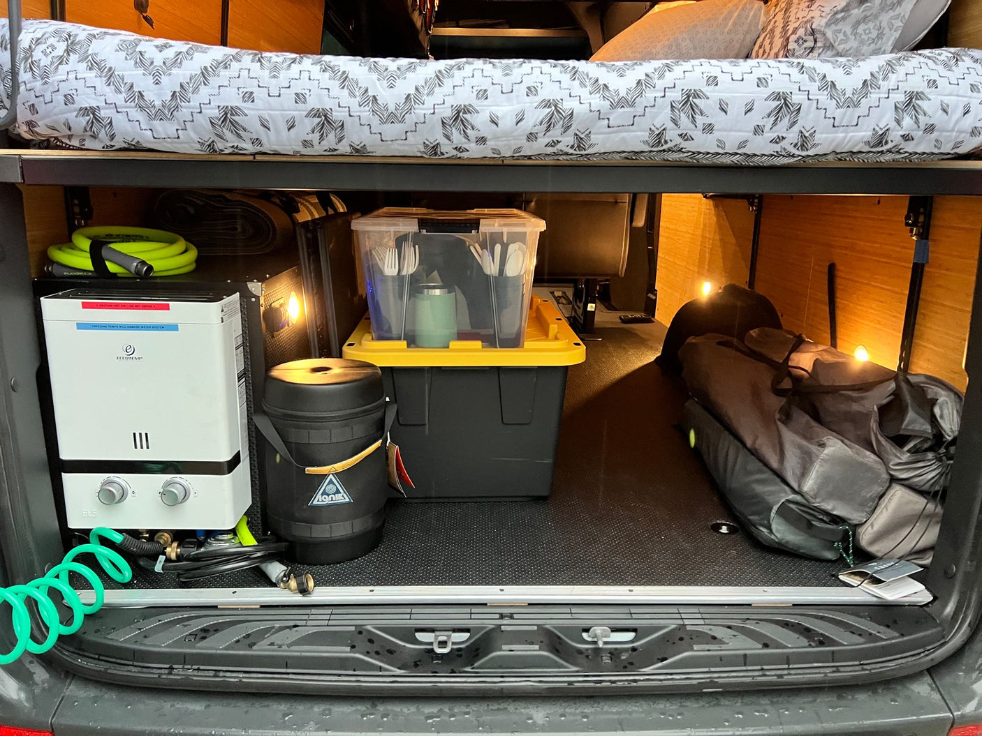RV rental efficiency: Compact camper van interior with raised bed, water heater, & organized storage for all your travel gear.
