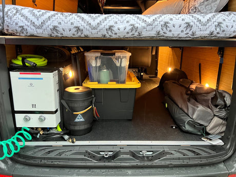 RV rental efficiency: Compact camper van interior with raised bed, water heater, & organized storage for all your travel gear.