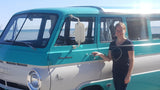 Happy woman with vintage teal & white Dodge Campwagon, an eye-catching RV rental.