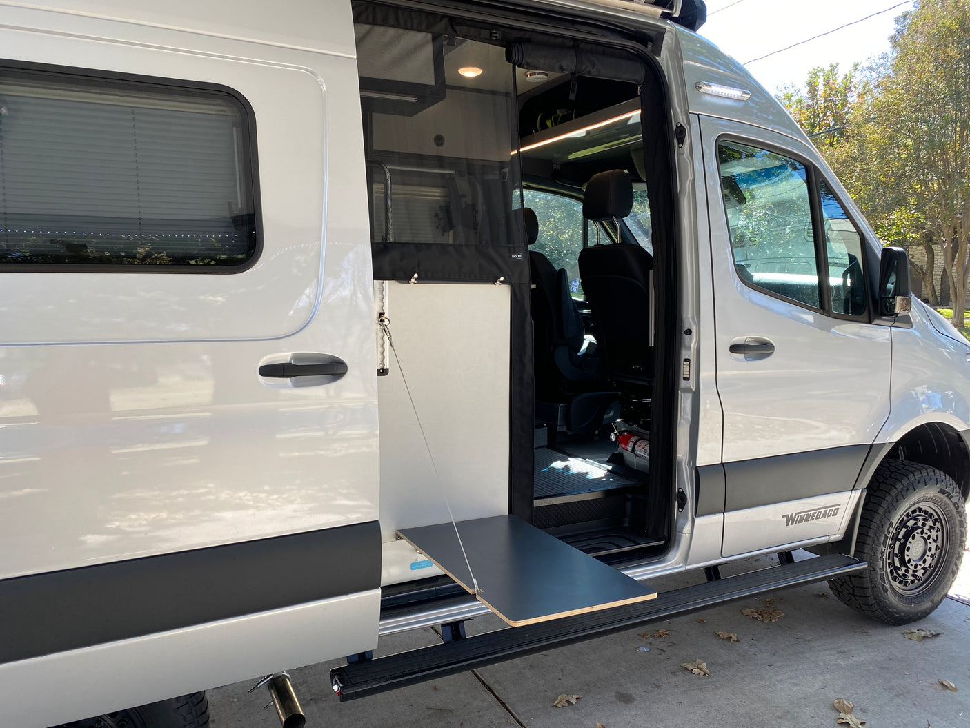 This RV rental's open side door reveals the camper van interior with a convenient pull-out table and steps.