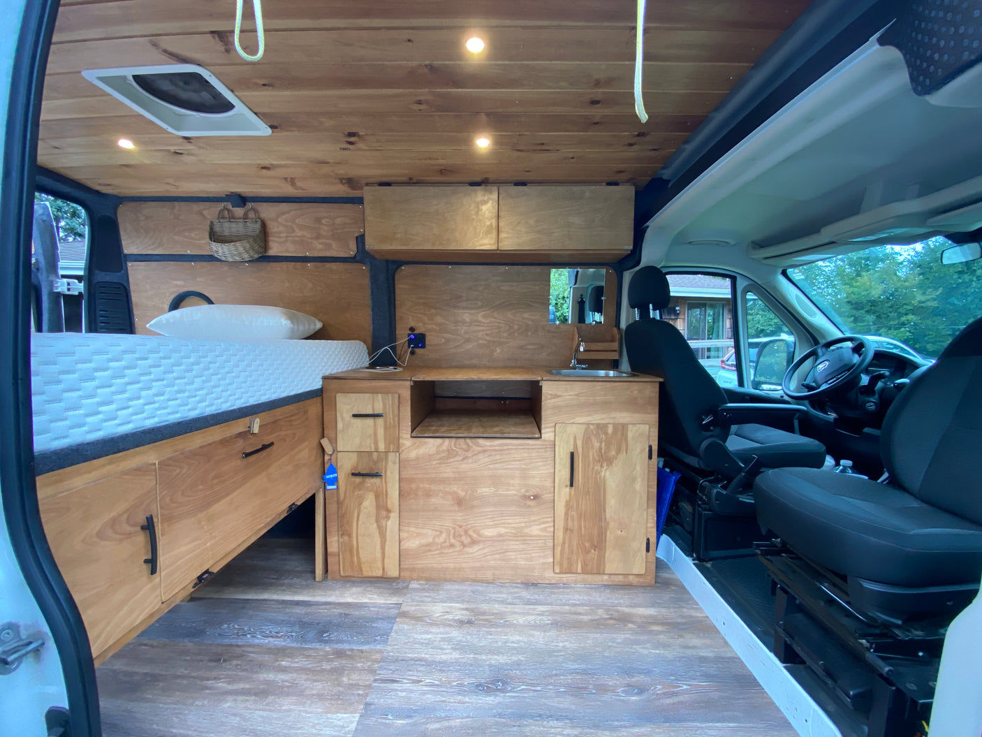 Spacious camper van interior, perfect for an RV rental adventure. Features a cozy bed, wooden kitchen area, and practical storage.