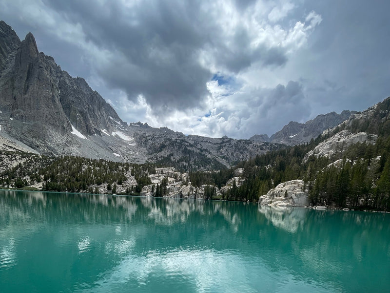  perfect for an RV rental outdoor adventure. Towering cliffs & blue sky.|A person stands by a serene mountain lake — photo 12