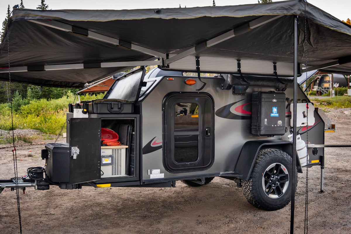 A grey overland camper trailer, perfect for rv rental adventures. Features a large awning, outdoor kitchen, and storage. — photo 7
