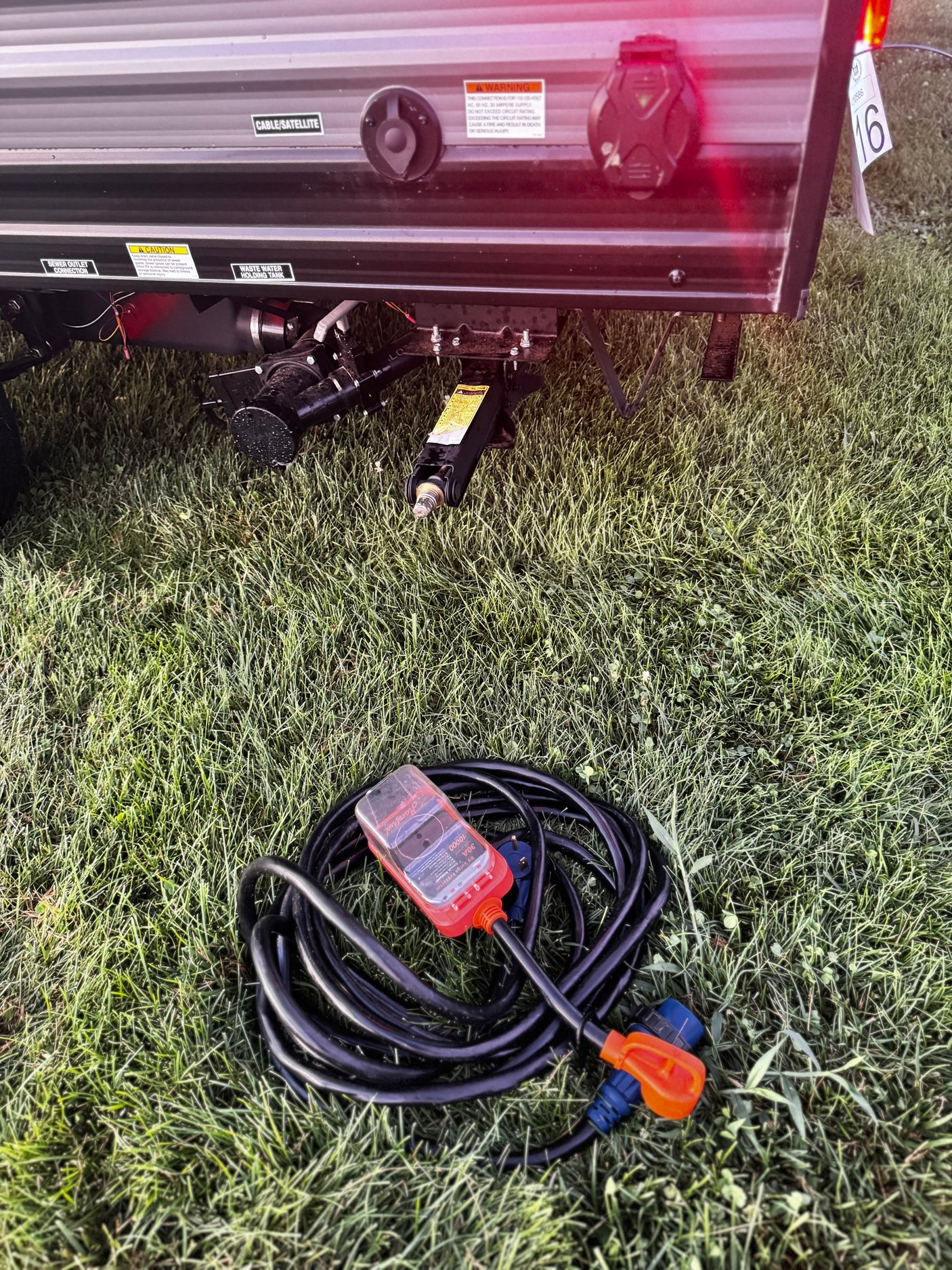 RV rental utility setup showing electrical connections, power cord with surge protector, and sewer/water outlets.