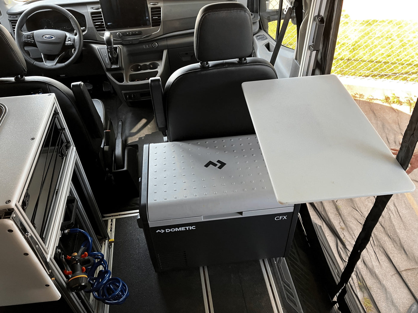 RV rental camper van interior showing a Dometic CFX fridge with attached portable table and water system. — photo 16