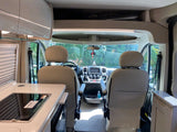RV rental interior: A spacious view showing the front cockpit with swivel seats and a compact kitchen counter.