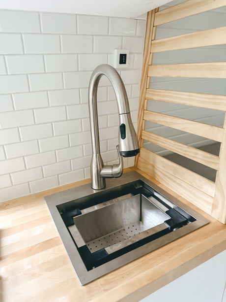 RV rental: Modern stainless steel kitchen sink and gooseneck faucet on a wood counter, with white subway tile backsplash.