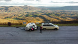Scenic Montvale mountain view with an RV rental setup: a minivan, teardrop trailer, and bikes parked at the overlook.