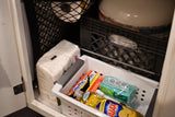 Compact RV rental storage: cabinet neatly organized with cleaning supplies like Ajax, sponges, and Hefty trash bags, plus paper products.