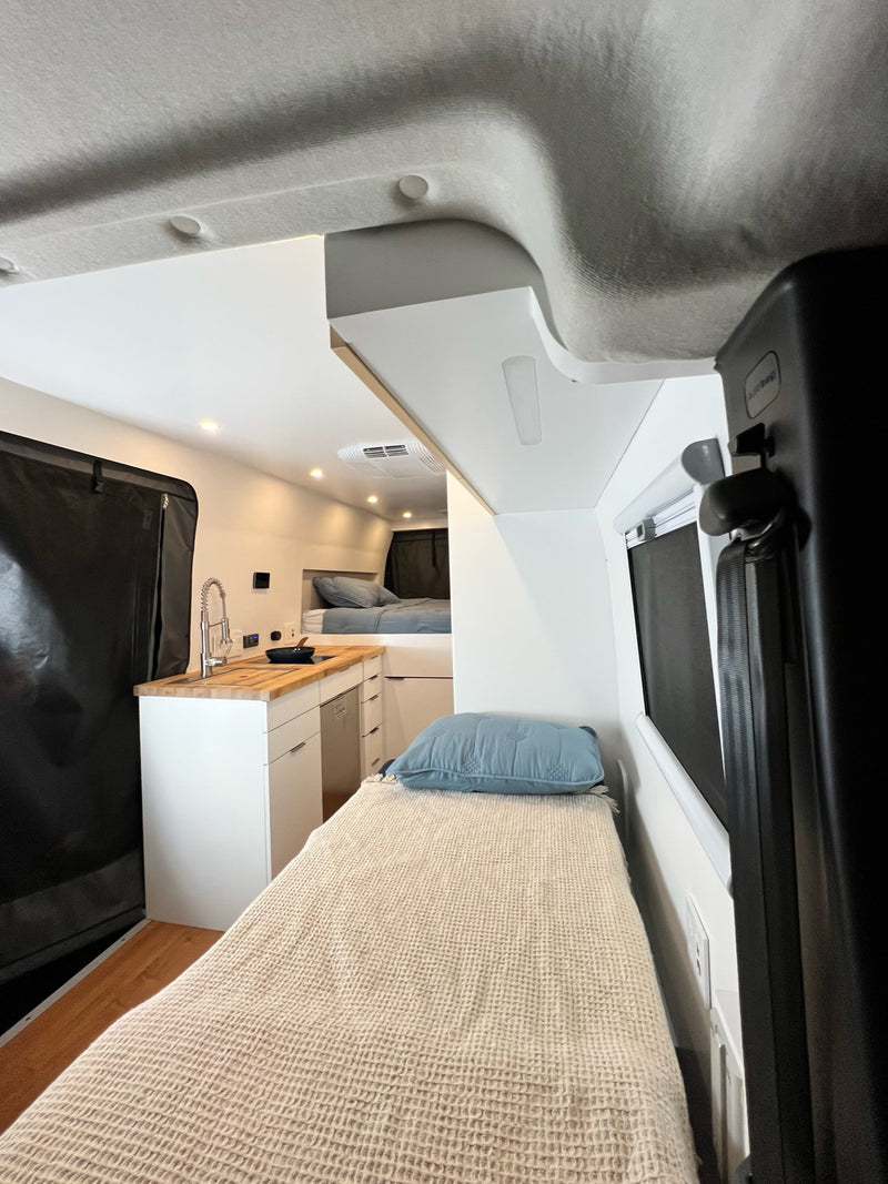 Bright RV rental interior: compact kitchen with wood counter/sink — photo 1