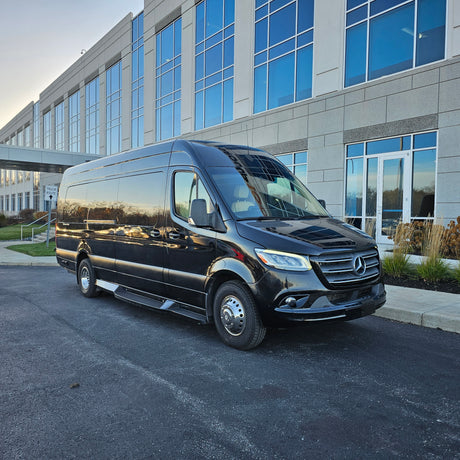 A black Mercedes-Benz Sprinter van, a versatile vehicle often used for corporate travel or rv rental, parked near a modern building.