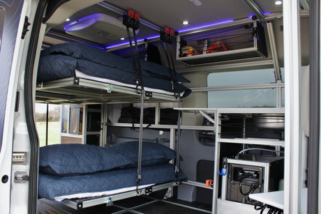 Modular RV rental interior featuring suspended bunk beds, smart storage, and integrated power for travel comfort.
