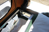 Inside a comfortable RV rental tent: bed with white/green bedding, mesh window, and orange canvas walls. Perfect for outdoor travel.