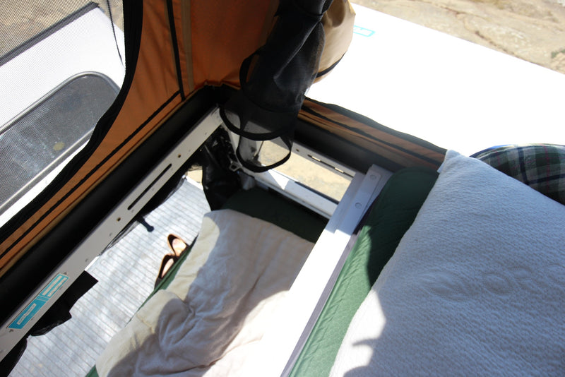 Inside a comfortable RV rental tent: bed with white/green bedding, mesh window, and orange canvas walls. Perfect for outdoor travel. — photo 9