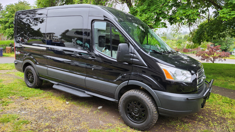 This black Ford Transit camper van, featuring off-road tires and custom wheels, stands ready for adventure as an RV rental. — photo 5