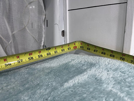 RV rental interior measurement: tape measure shows ~56-70 inches across plush blue fabric, likely a bed or seating area.