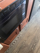 RV rental kitchen: built-in microwave, wooden cabinetry, and textured wood-look flooring for a cozy interior.